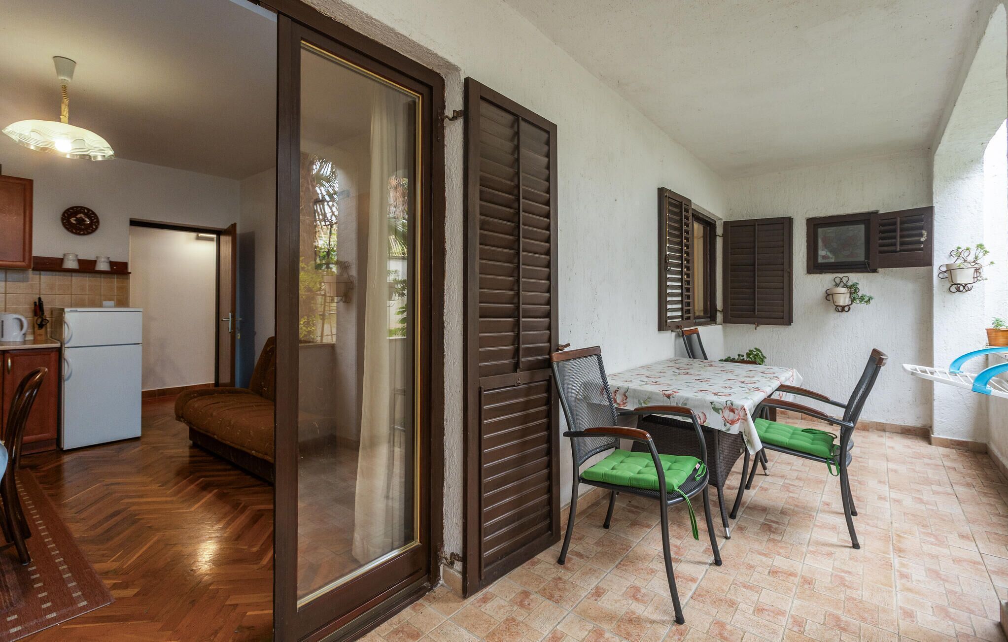 A compact kitchen with a refrigerator, a dining table with chairs, and a sliding glass door leading to a balcony.