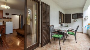 A compact kitchen with a refrigerator, a dining table with chairs, and a sliding glass door leading to a balcony. - Pet friendly apartment in Porec with WiFi (Porec)