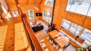 Eine Holzhütte mit Schlafzimmer auf dem Dachboden, Essbereich und Kamin.