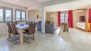 Un amplio espacio de estar con una mesa de comedor, sillas, un sofá y un televisor.
