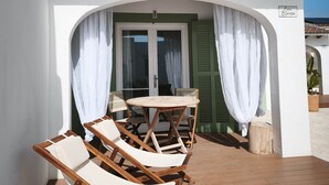 A patio with wooden deck, white walls, and a green door.
