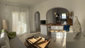 A modern kitchen with a central island, bar stools, and a dining area with a wooden table and chairs.