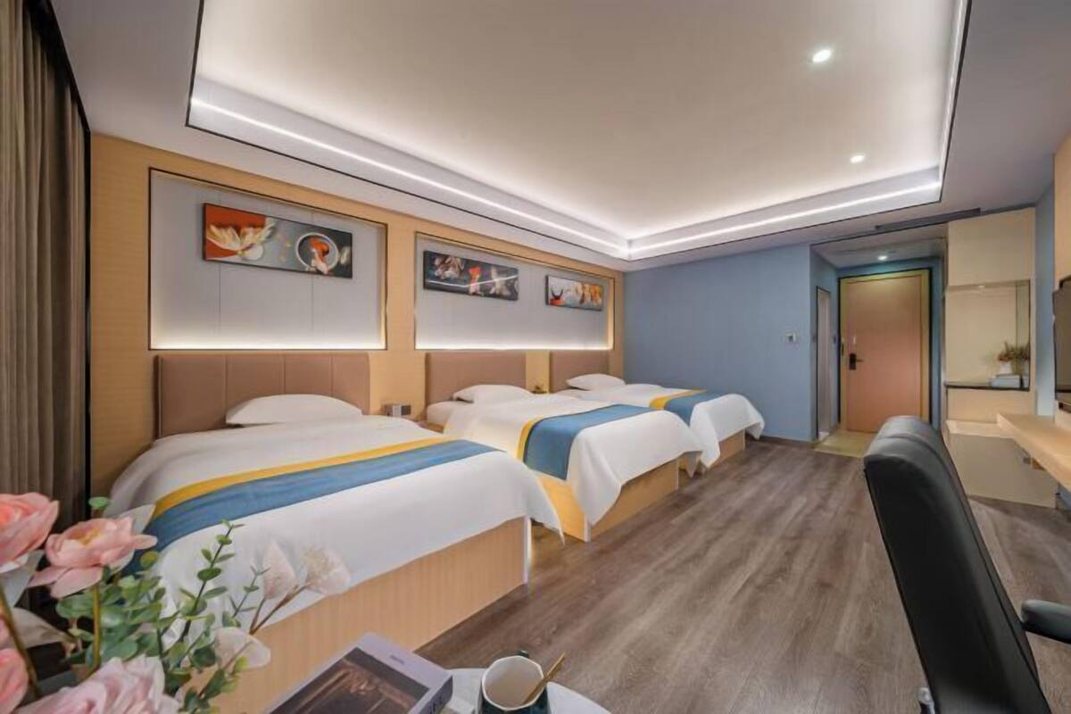 A hotel room with two beds, a desk with a chair, and artwork on the walls.