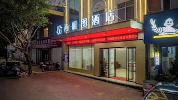 A hotel with a prominent sign, a red awning, and a visible entrance.