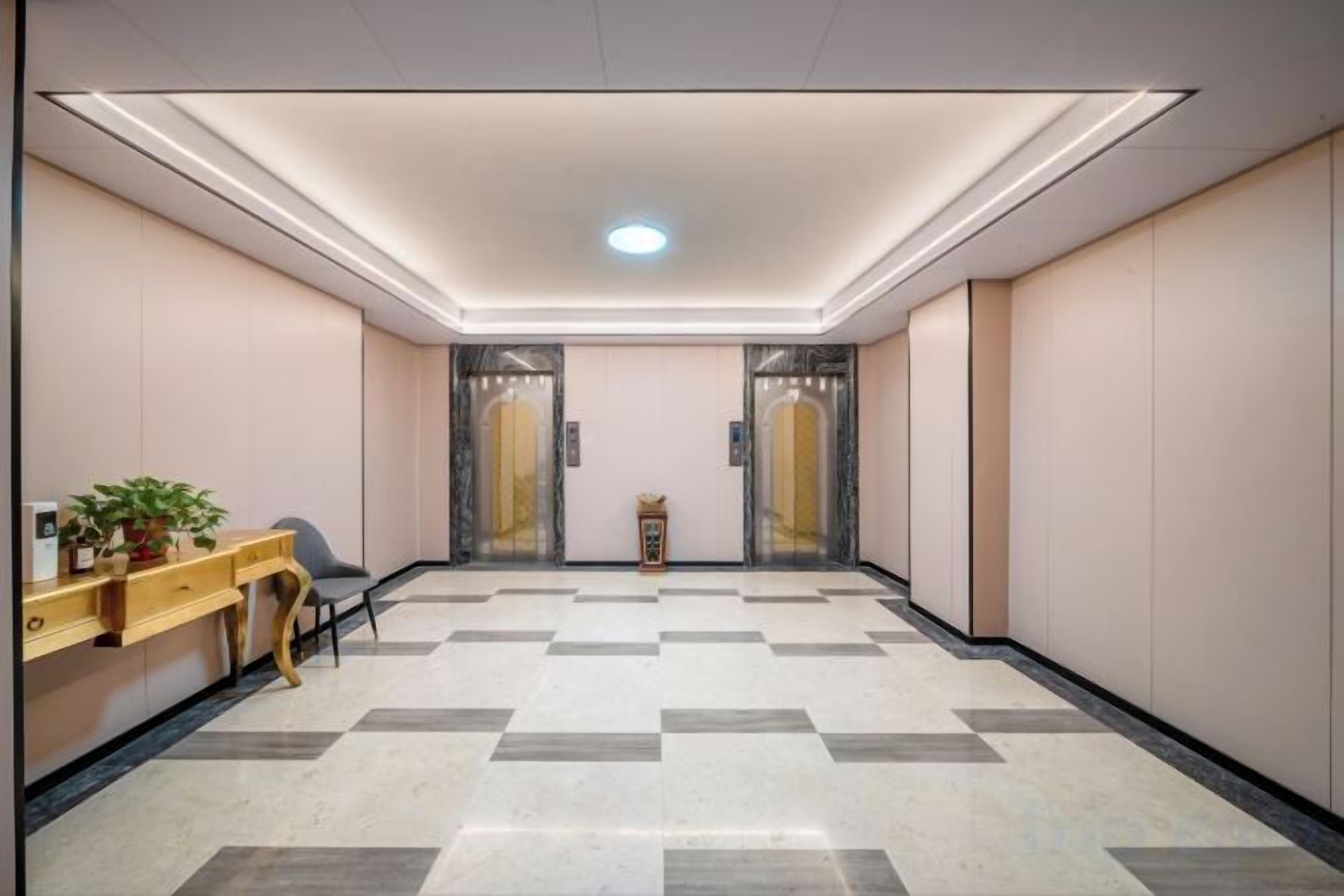 Un vestíbulo de hotel con una recepción, una planta, una zona de estar y una máquina de registro.