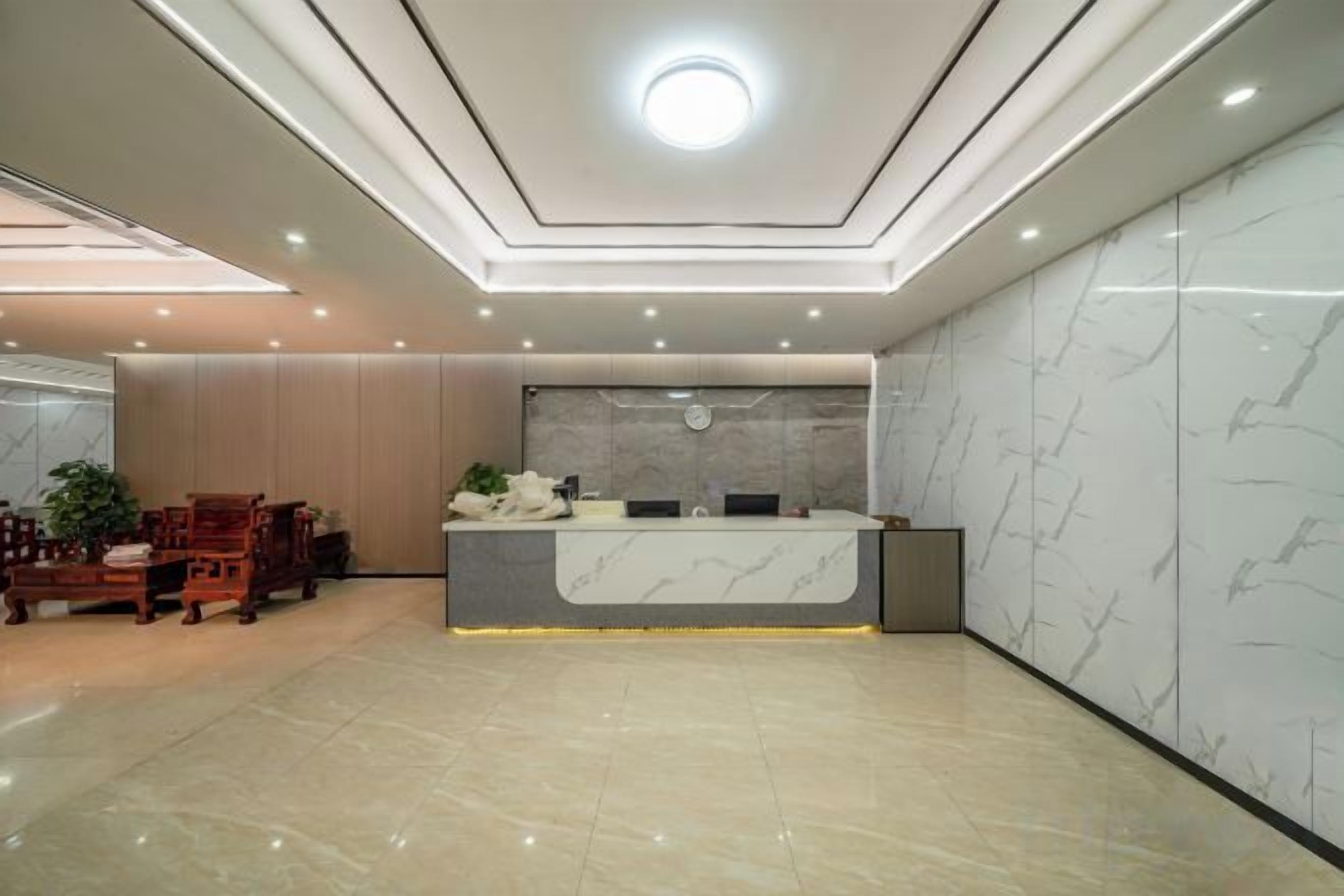 A modern reception area with a marble reception desk, wooden furniture, and a clean, polished floor.