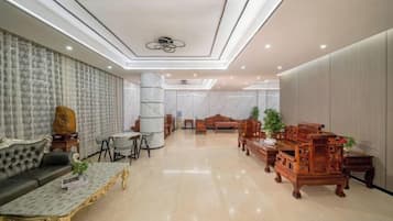 A hotel lobby with a sofa, chairs, a coffee table, and a reception desk.