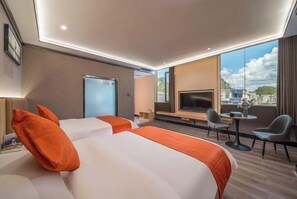 Une chambre d’hôtel avec deux lits, une télévision, une petite table et une vue sur la ville.