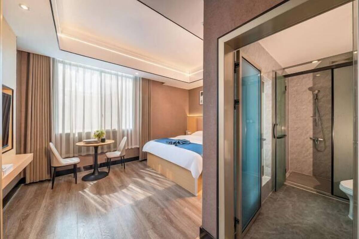 A hotel room with a bed, bedside table, chair, and a small round table with chairs.
