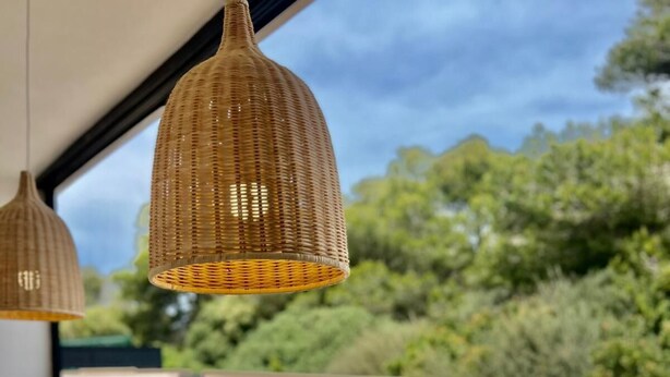 A wooden table with a bowl, two wicker pendant lights, and a view of greenery and a building in the background. - Son Carrió 6, Son Carrió 6 - Sa Perdiu 6 (Son Carrió)