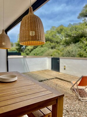 A wooden table with a bowl, two wicker pendant lights, and a view of greenery and a building in the background. - Son Carrió 6, Son Carrió 6 - Sa Perdiu 6 (Son Carrió)