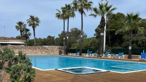 A swimming pool with a wooden deck, surrounded by palm trees and lounge chairs. - Son Carrió 6, Son Carrió 6 - Sa Perdiu 6 (Son Carrió)