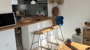A modern kitchen with a wooden island, bar stools, and a dining table. - Cales de Menorca 3, Cales de Menorca 3 - Cala Morell (Cala Blanca)
