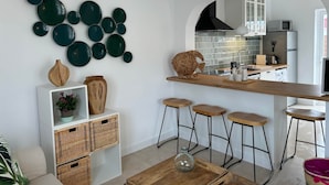 Eine moderne Küche mit einer zentralen Kochinsel, Barhocker, einer Wanddekoration und einer Holzskulptur.