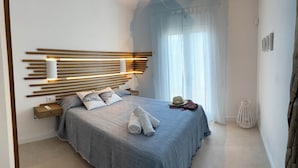 Ein modernes Schlafzimmer mit Bett, Nachttischen, einer Kopfteilbeleuchtung und einem großen Fenster mit transparenten Vorhängen.