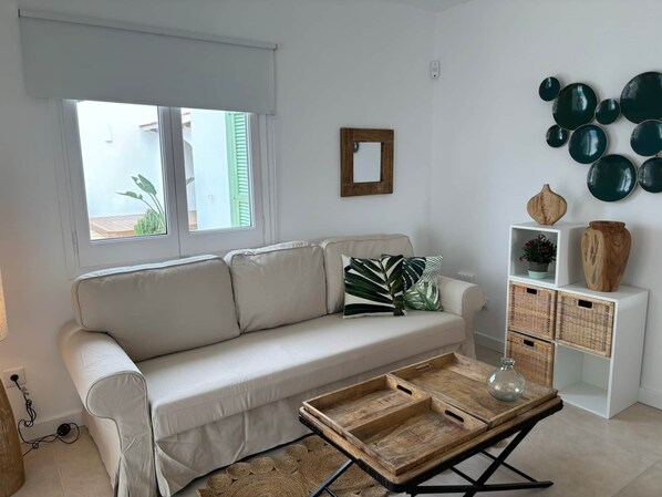 A modern living room with a beige sofa, a wooden coffee table, and a white console table with wicker baskets.