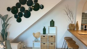 Een moderne keuken met een houten barstoel, een witte bank en een rond spiegel bevestigd aan de muur.