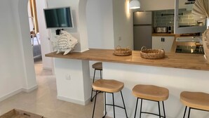 Una cocina moderna con una isla de madera, taburetes de bar, un televisor y una gran decoración de pez.