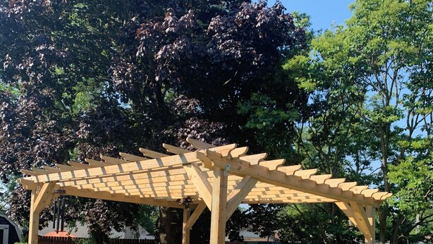 A wooden pergola with a bench, surrounded by potted plants and a gravel pathway. - Near O’Hare, King Bed, Spacious, Great Backyard, WiFi, AC (Wood Dale)