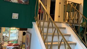 A staircase with a golden railing leading to a room with a green wall and a painting. - Near O’Hare, King Bed, Spacious, Great Backyard, WiFi, AC (Wood Dale)