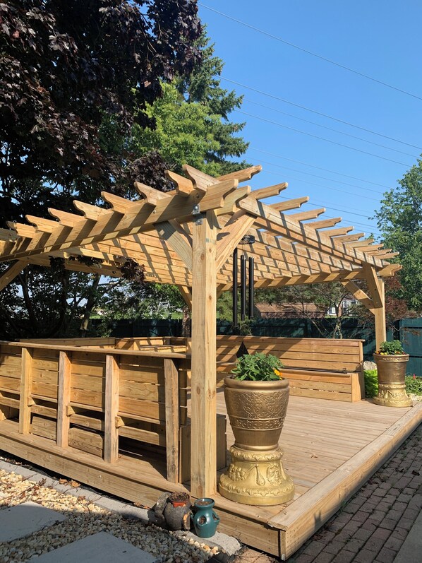 Relax beneath the shaded pergola, surrounded by lush greenery and vibrant flowers.
