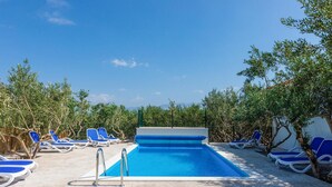 A swimming pool with blue water, surrounded by lounge chairs and trees. - Beautiful home in Supetar (Supetar)