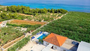An aerial view of a property with a swimming pool, terraced gardens, and a view of the sea. - Beautiful home in Supetar (Supetar)