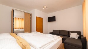 A hotel room with a bed, a sofa, a TV, and a wardrobe. - Beautiful home in Supetar (Supetar)