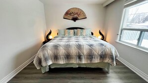 A bedroom with a bed, a window, and a wall-mounted fan.