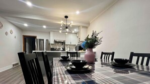 A dining area with a checkered tablecloth, black chairs, and a vase with flowers.