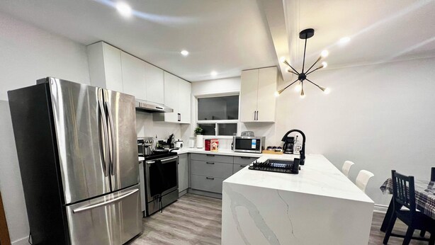 A modern kitchen with stainless steel appliances, a central island, and a dining area with a table and chairs.