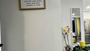 A hallway with a welcome sign, a vase with flowers, and a mirror.