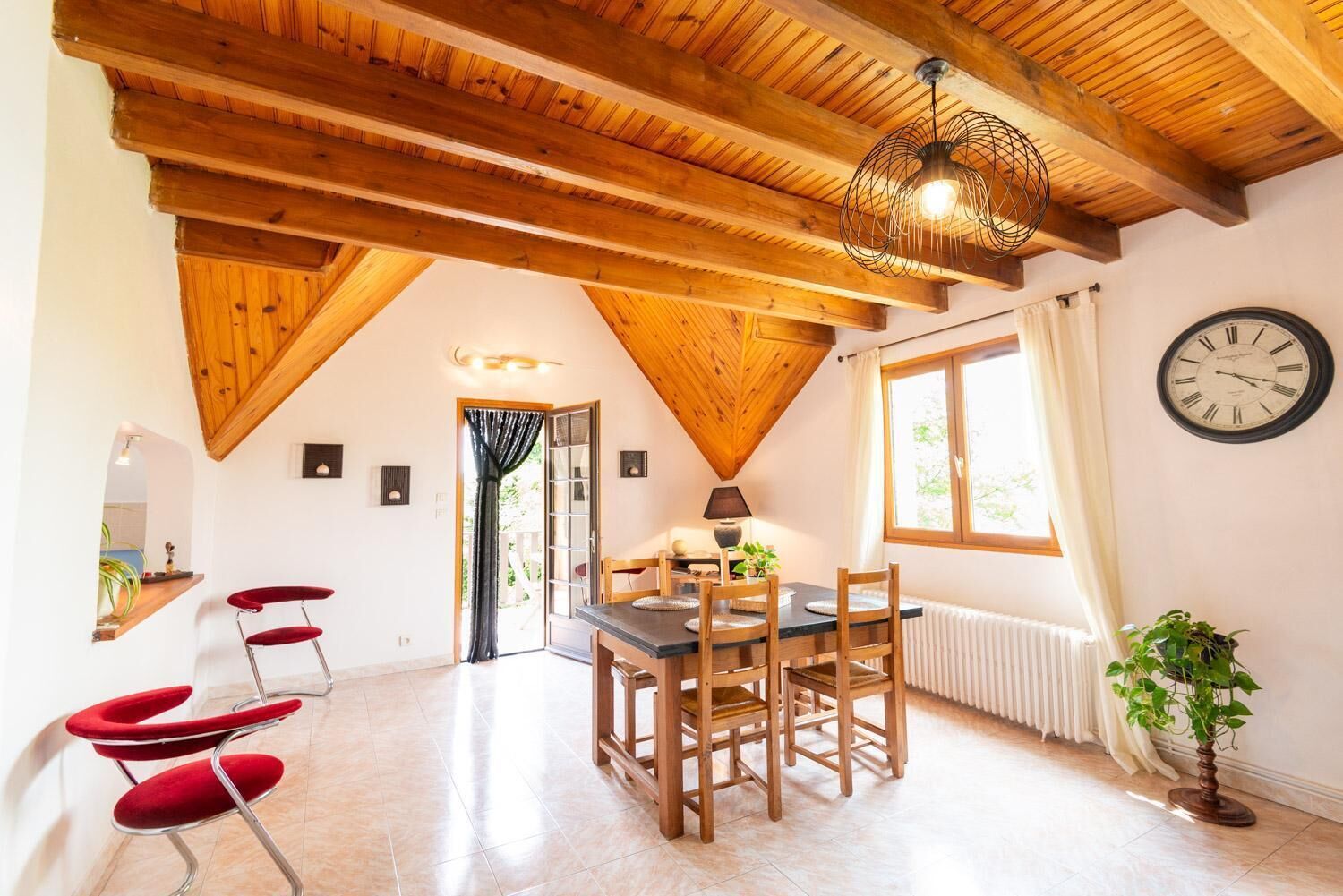 Een gezellig eetgedeelte met een houten tafel en stoelen, een plafondventilator en een klok aan de muur.
