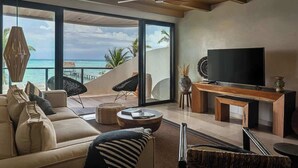 Un soggiorno spazioso con un'ampia televisione, posti a sedere confortevoli e vista sull'oceano.