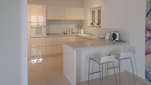 Eine moderne Küche mit Kochinsel, Barhocker, Backofen und kleinem Spülbecken.