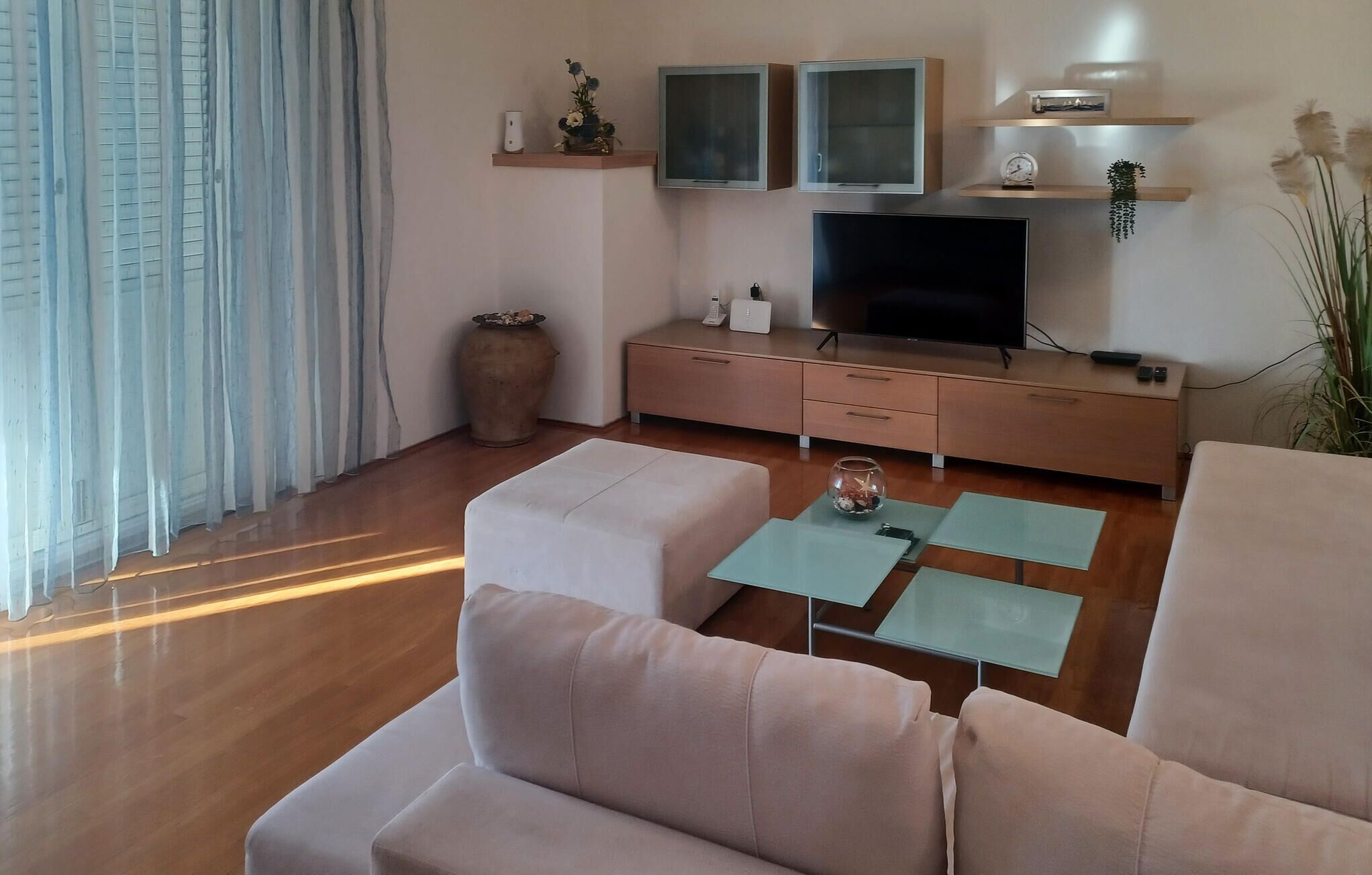 Un salon moderne doté d’un téléviseur à écran plat, de deux canapés, d’une table basse et d’un meuble en bois orné d’objets décoratifs.