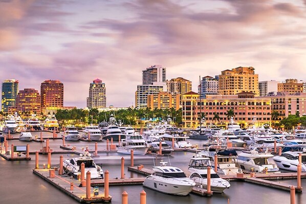 A marina with numerous yachts docked, surrounded by high-rise buildings.