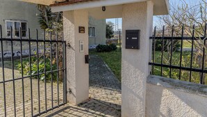Una entrada cerrada por un portón a un edificio, con un camino de adoquines que lleva a una puerta.
