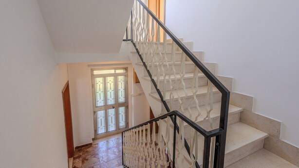 Una escalera con barandilla blanca y escalones color beige que conducen a una plataforma.