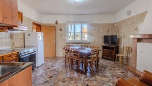 Una cocina compacta con comedor, estufa, refrigerador y televisor.