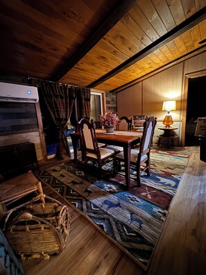 Un rincón comedor acogedor con una mesa de madera, sillas y un tapete estampado.