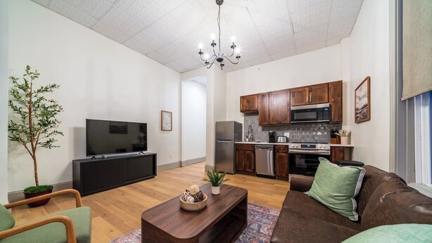 Una sala moderna con una televisión de pantalla plana, una mesa de centro de madera y un sofá de cuero marrón.