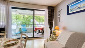 A hotel room with a balcony, a dining table with chairs, a sofa, a TV, and a lamp. - Amazing apartment in La Rochelle with WiFi (La Rochelle)