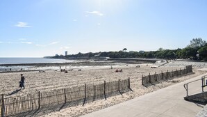 A beach with a wooden fence, a concrete walkway, and a distant cityscape. - Amazing apartment in La Rochelle with WiFi (La Rochelle)