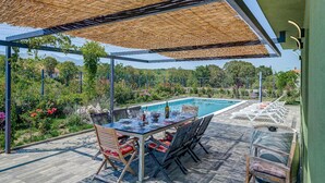 A poolside area with a table set for dining, chairs, and a covered seating area.