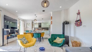 A modern living room with a dining area, a kitchen in the background, and a fireplace.