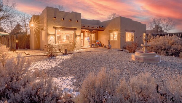 A modern house with a gravel driveway and a decorative stone structure in the front yard.