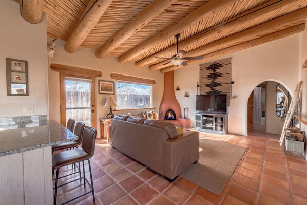 Amplia sala de estar con chimenea, cocina y comedor con taburetes de bar.