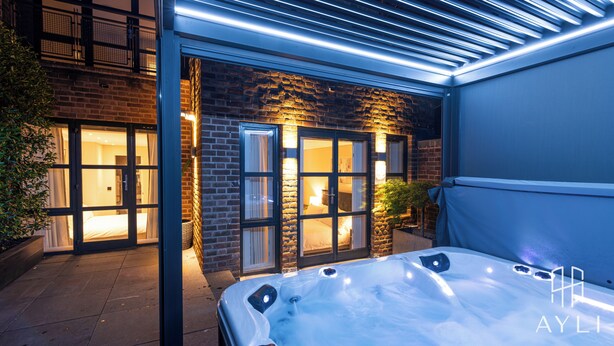 A modern hotel with a glass door entrance, a hot tub, and a brick facade. - AYLI (London)