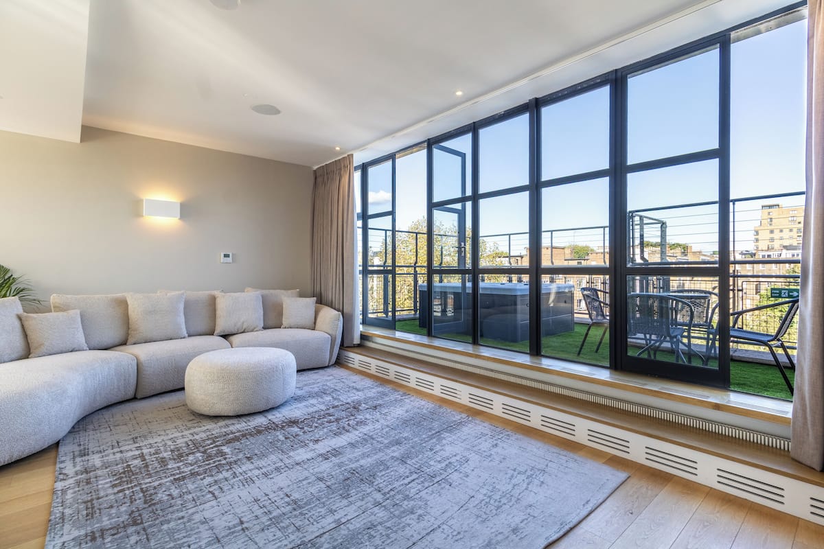 A modern living room with a large window, a sectional sofa, and a patterned rug.